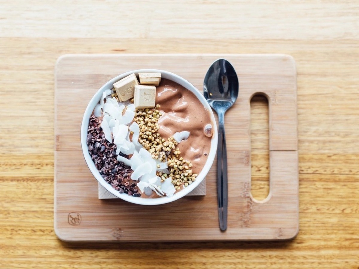 Flat lay of a smoothie bowl topped with cacao nibs, coconut and granola